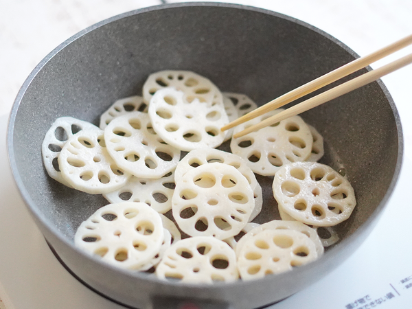 輪切りにしたれんこんをフライパンで炒める